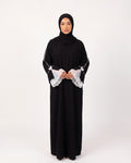 Noura Pearl Lace Abaya in Schwarz – lange Abaya mit weißen Spitzen- und Schleifendetails an den Ärmeln